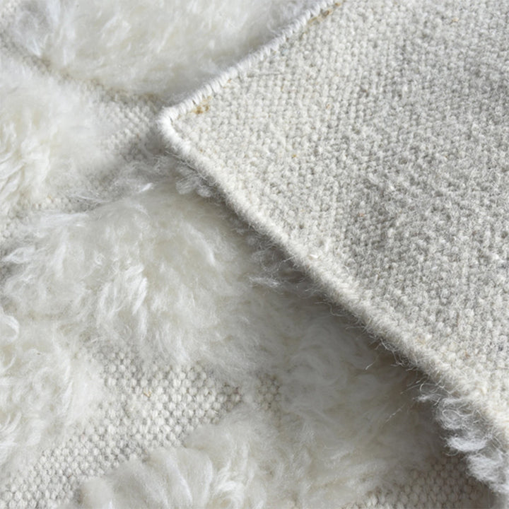 Til handwoven New Zealand wool flatweave rug with an ivory diamond lattice and dots, in a living room