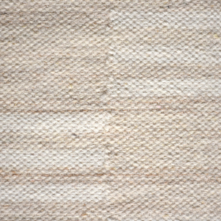 Parat handwoven wool rug in cream and oatmeal with vertical block stripes, in a bedroom