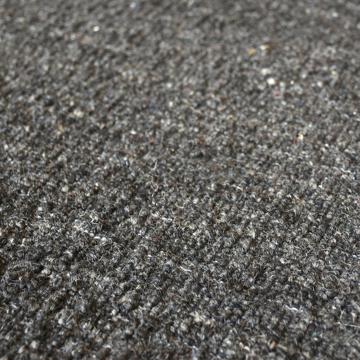 Saada handwoven flat wool rug in solid stone beige with charcoal, in a living room