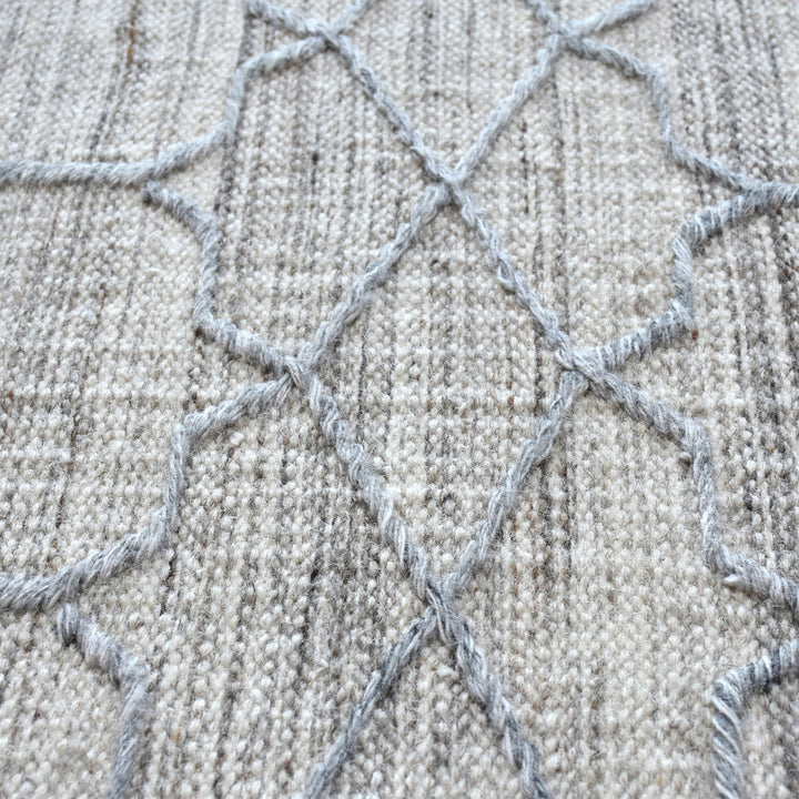 Bel handwoven wool and viscose rug with grey trellis lines on light grey, in a living room