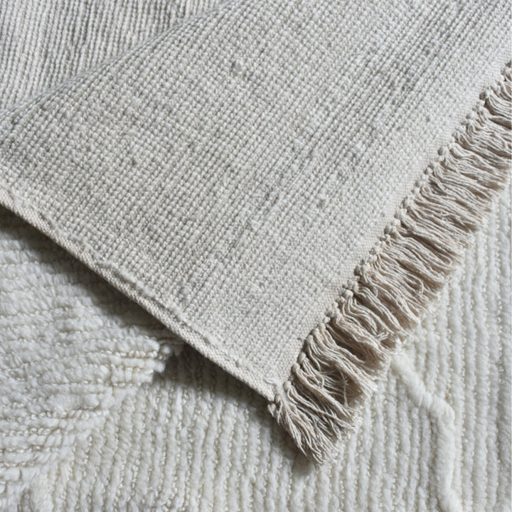 Kangan tufted wool rug with a tonal carved Moroccan lattice in bone ivory, in a bedroom