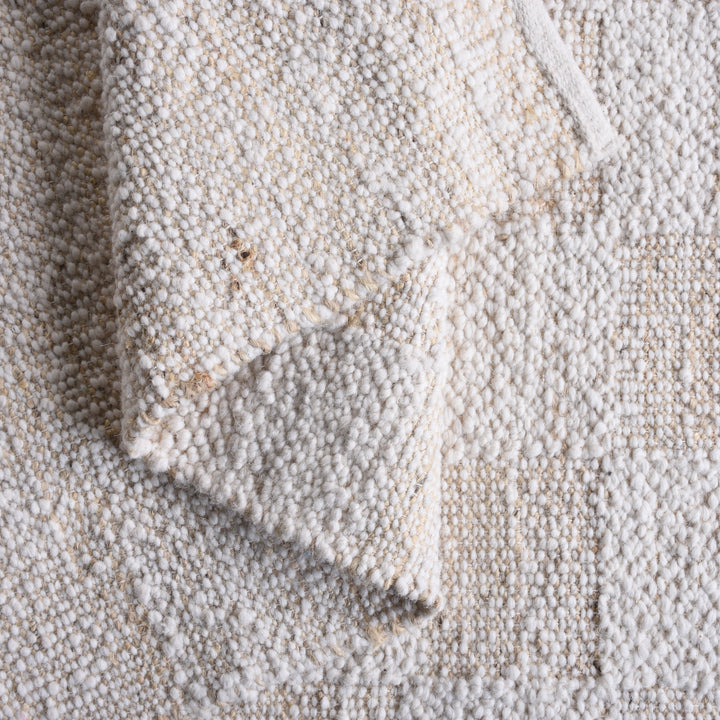 Chaupar handwoven wool and jute rug in greige and ivory with a checkerboard patch texture, in a study