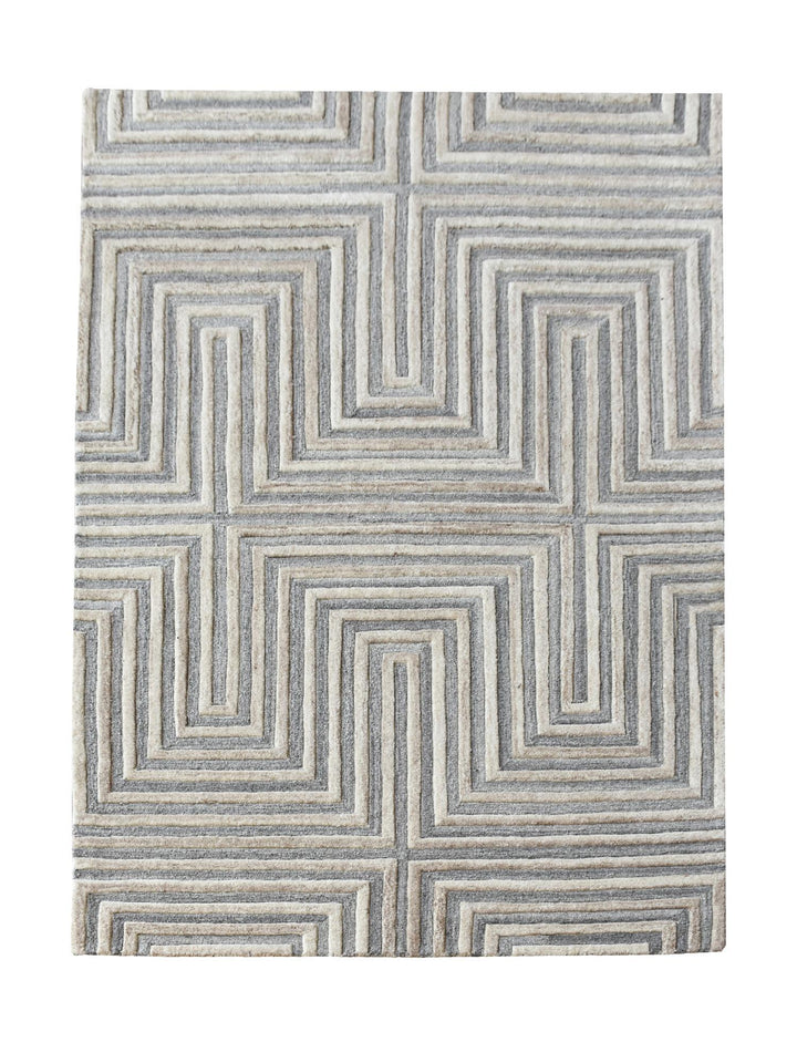 Raasta hand-tufted sand beige wool rug with carved concentric maze lines, in a living room