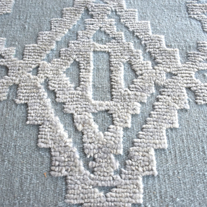 Mor hand-knotted wool rug with ivory raised diamonds on duck egg blue, in a bedroom