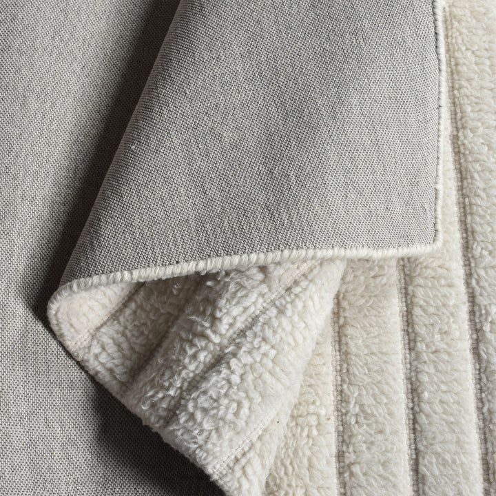 Sopan handwoven New Zealand wool rug with broad ivory ridges, in a living room