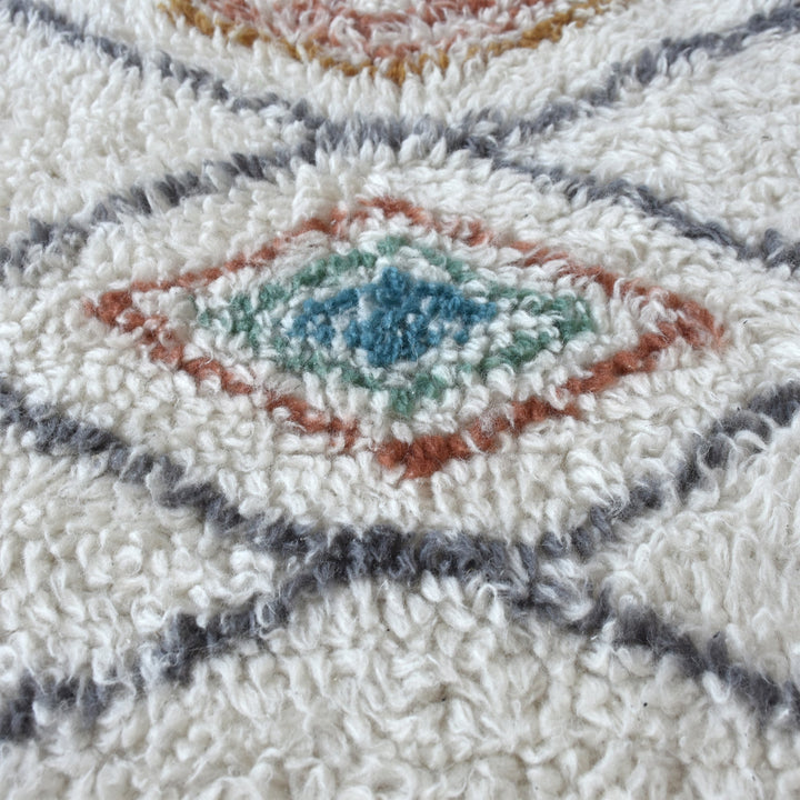 Mela tufted New Zealand wool rug with an ivory lattice and rust, teal and charcoal diamonds