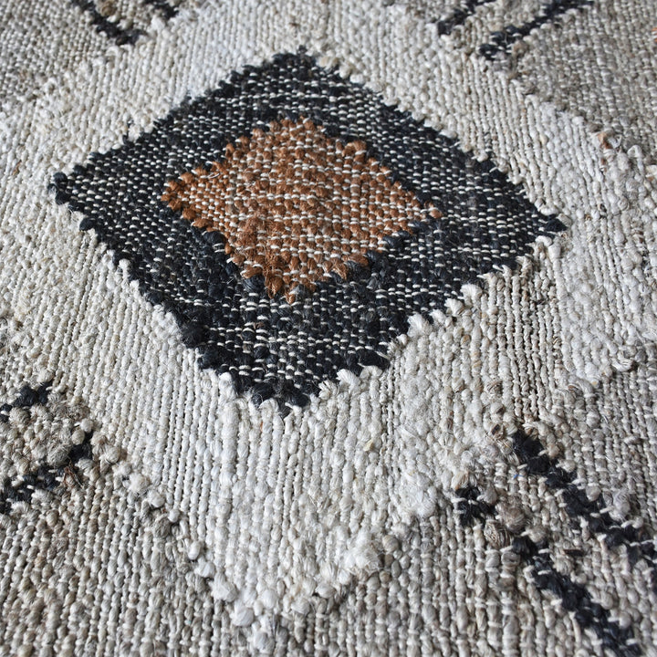 Terrain flatweave hemp rug with grey ground and terracotta and black motifs, in an entryway
