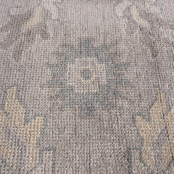 Yaad hand-knotted wool rug with distressed tribal medallions in pale taupe and rust, in a dining room