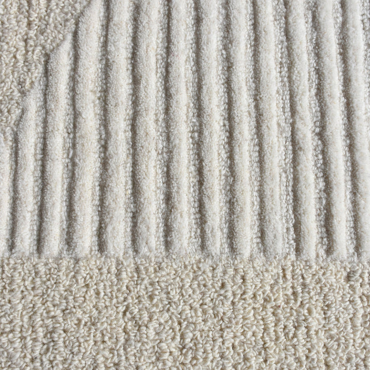 Archway handwoven ivory wool rug with carved arc lines, in a living room