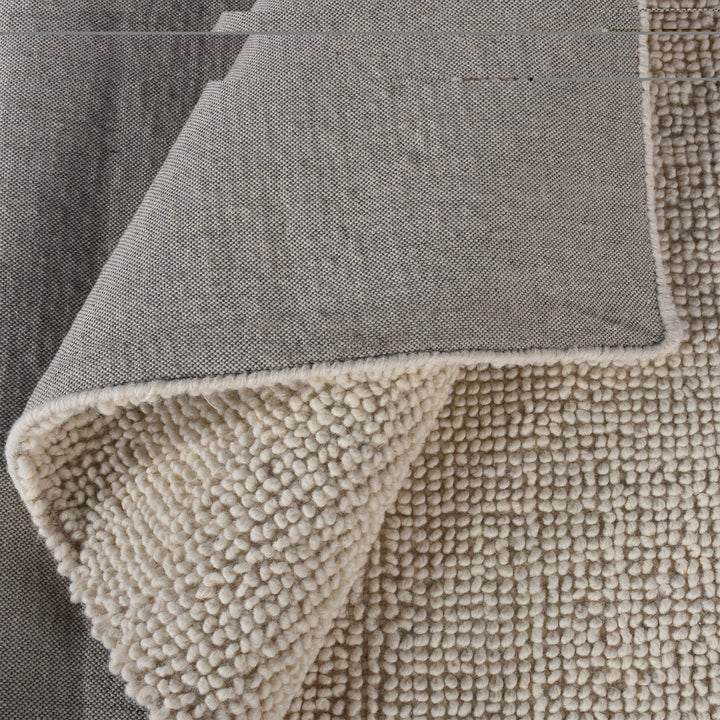 Lakeer handwoven ridged wool rug in oatmeal, tone on tone, in a bedroom