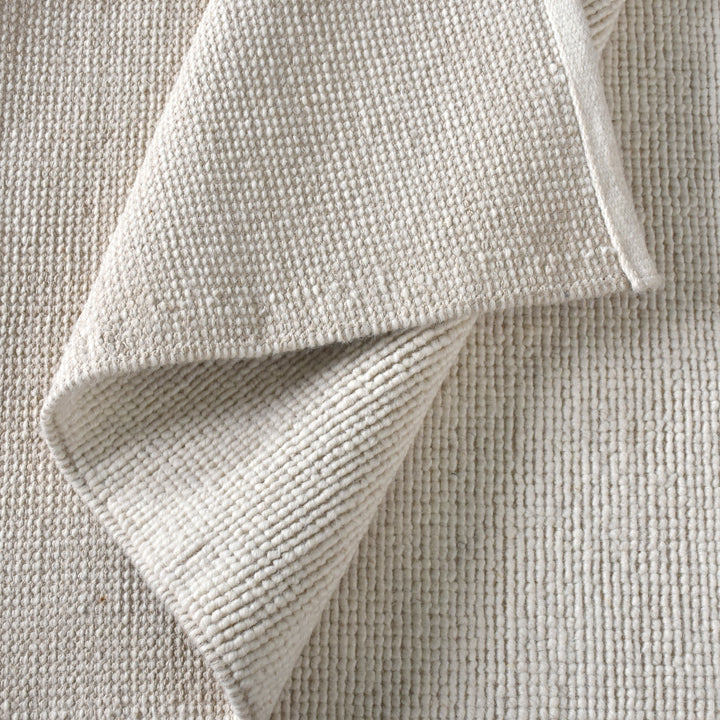 Mist handwoven pale stone wool rug with a chunky looped weave, in a living room