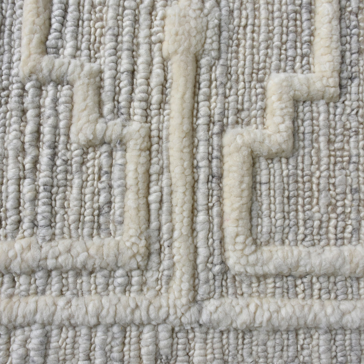 Chattan handwoven New Zealand wool rug with raised ivory diamonds on stone grey, in a living room