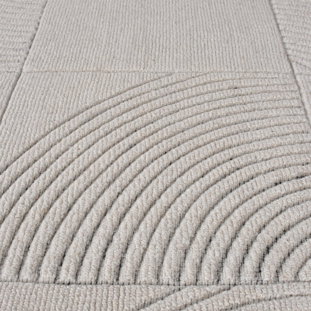 Seashell handwoven ivory wool rug with carved concentric arc tiles, in a bedroom
