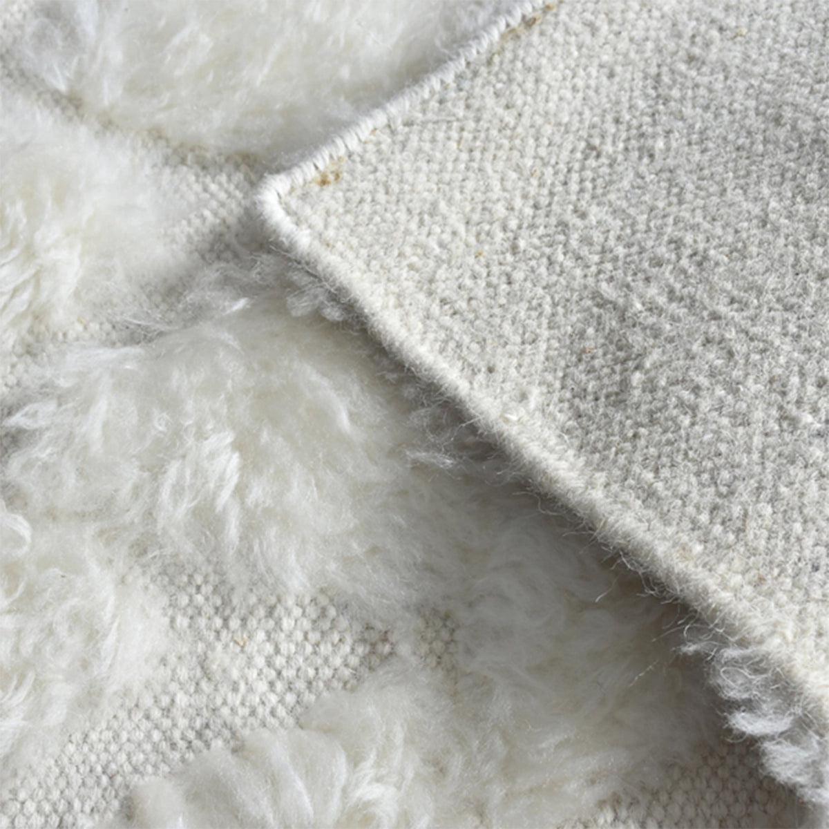 Til handwoven New Zealand wool flatweave rug with an ivory diamond lattice and dots, in a living room