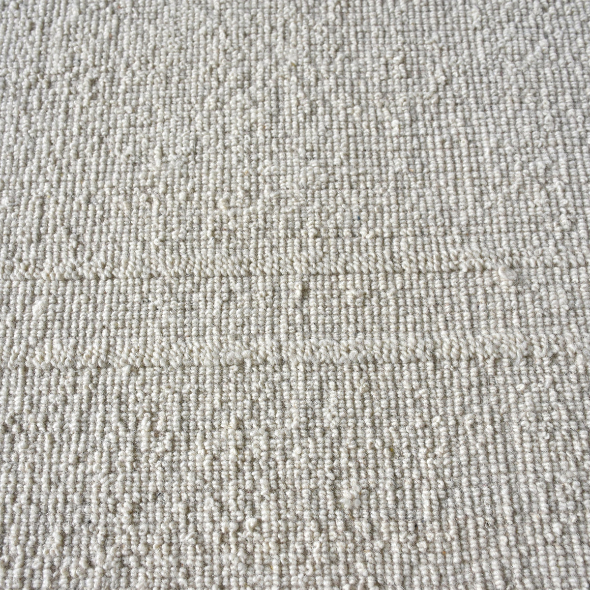 Margin handwoven ivory wool rug with a raised tonal border, in a living room