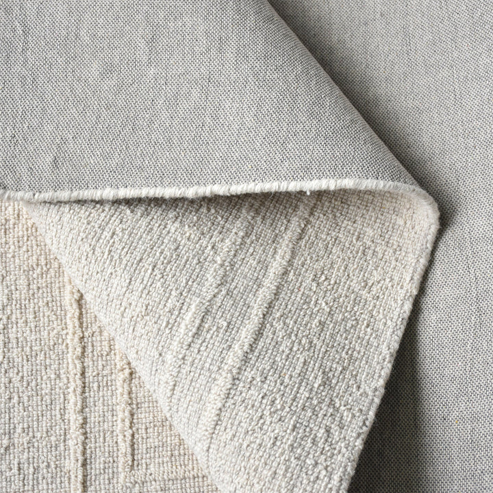 Margin handwoven ivory wool rug with a raised tonal border, in a living room