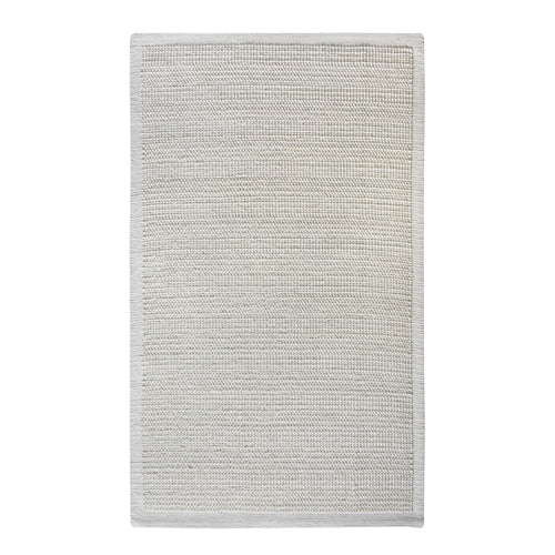 Basket handwoven cream wool rug with basketweave texture and tonal border, in a bedroom