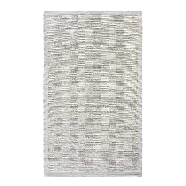 Basket handwoven cream wool rug with basketweave texture and tonal border, in a bedroom