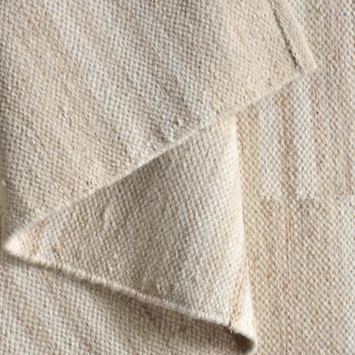 Parat handwoven wool rug in cream and oatmeal with vertical block stripes, in a bedroom