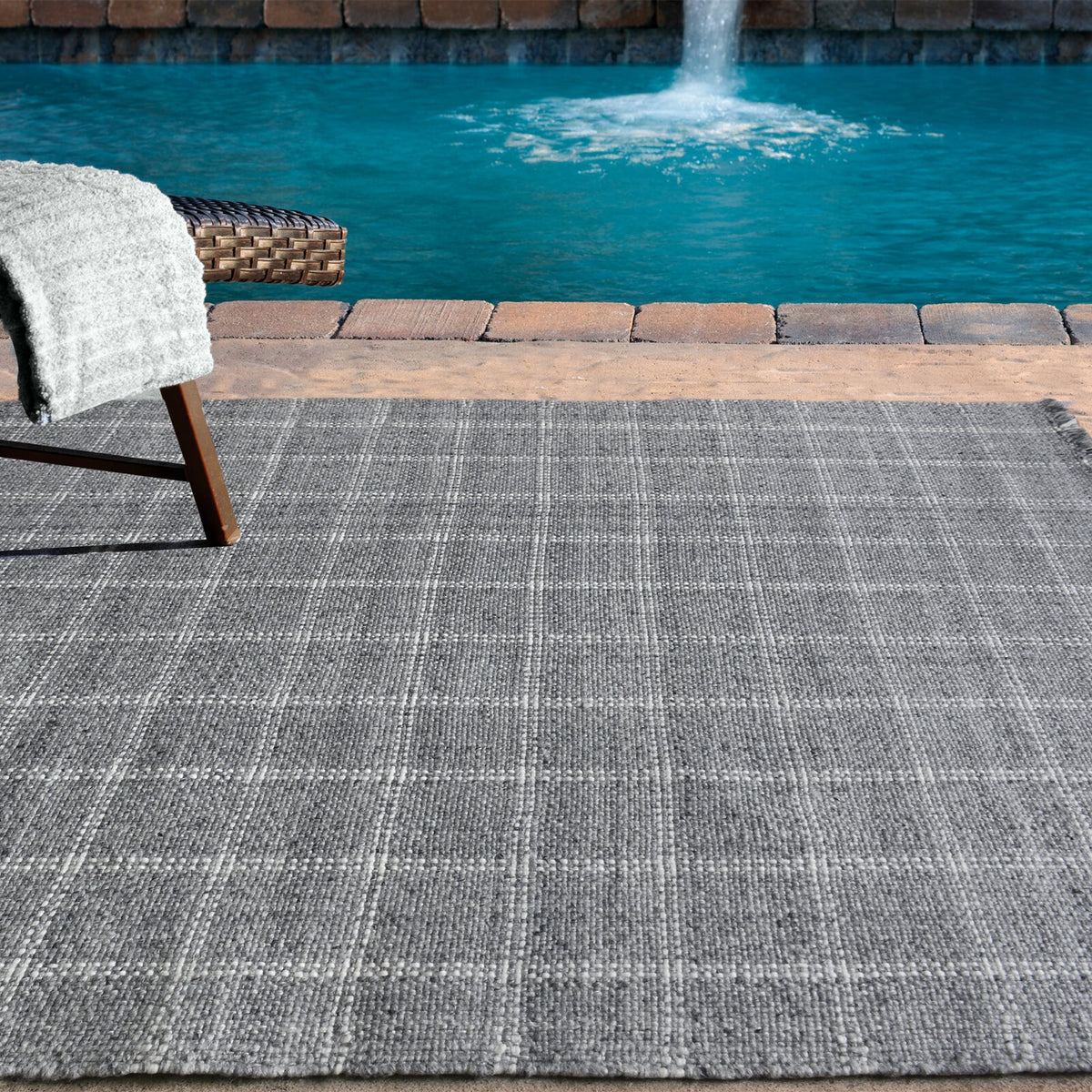 Pavilion handwoven slate grey and ivory recycled PET rug with a window-pane check, on a patio