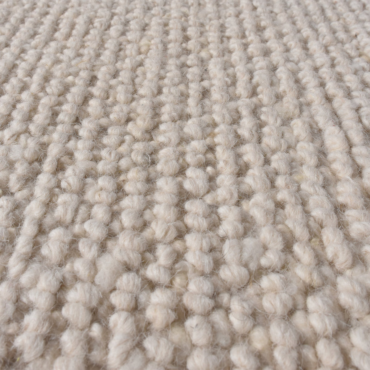 Bunai handwoven wool rug with a chunky looped bouclé surface in oatmeal, in a living room