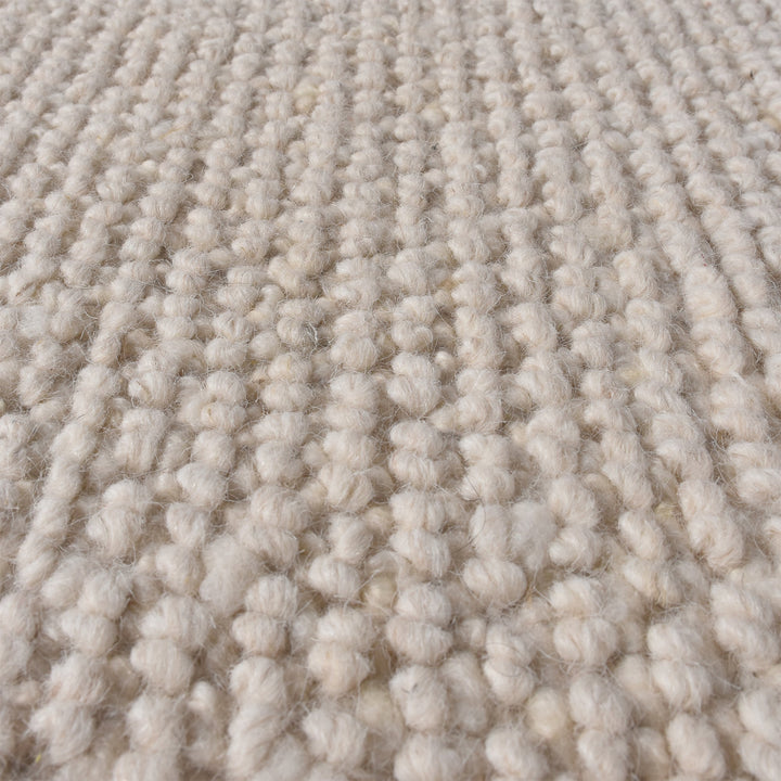 Bunai handwoven wool rug with a chunky looped bouclé surface in oatmeal, in a living room