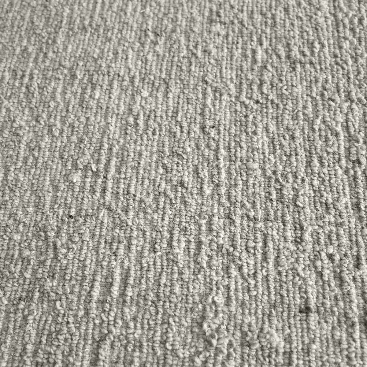 Saada handwoven flat wool rug in solid stone beige with charcoal, in a living room