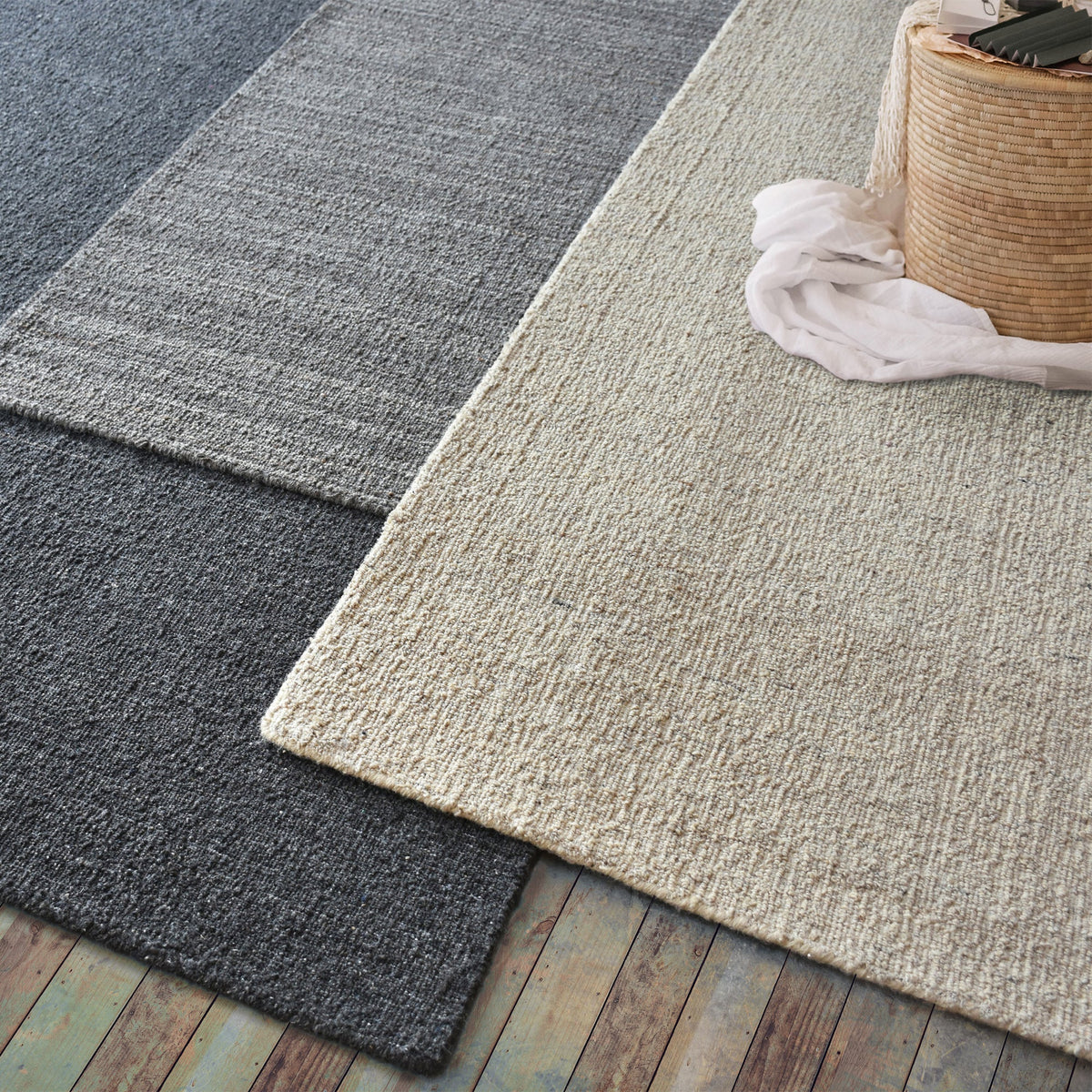 Saada handwoven flat wool rug in solid stone beige with charcoal, in a living room