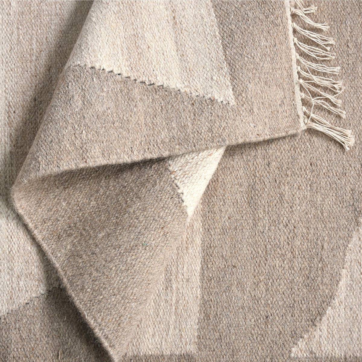 Chhatri handwoven wool rug with bold ivory and beige arch blocks, in a living room