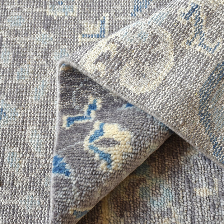 Kairi hand-knotted wool rug with blue paisley on a distressed taupe ground, in a living room