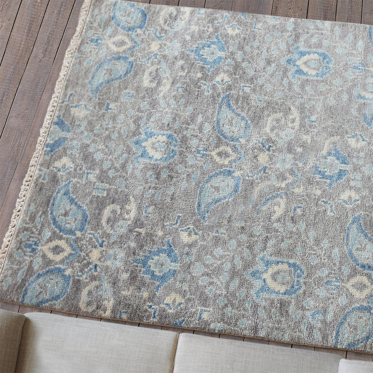 Kairi hand-knotted wool rug with blue paisley on a distressed taupe ground, in a living room
