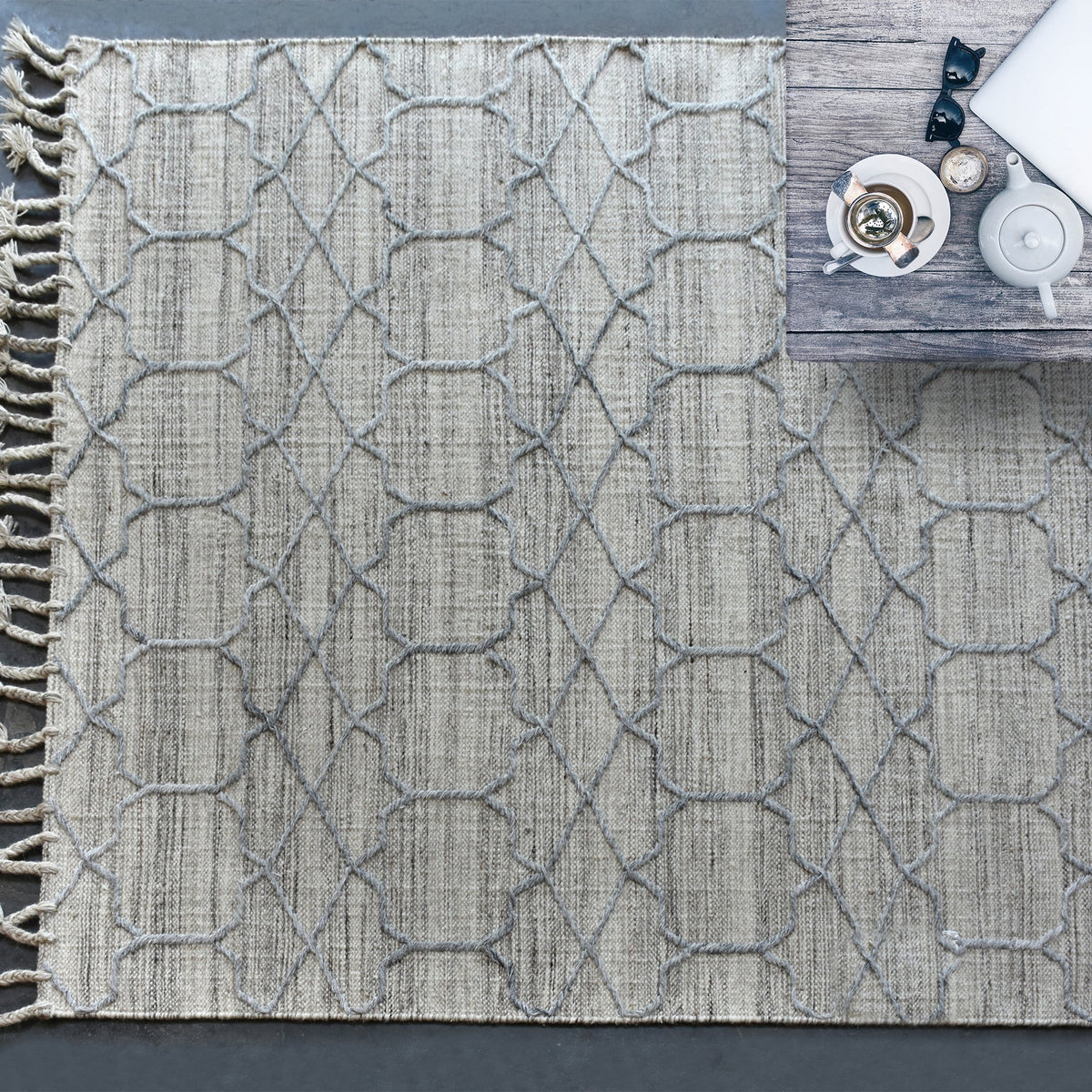 Bel handwoven wool and viscose rug with grey trellis lines on light grey, in a living room