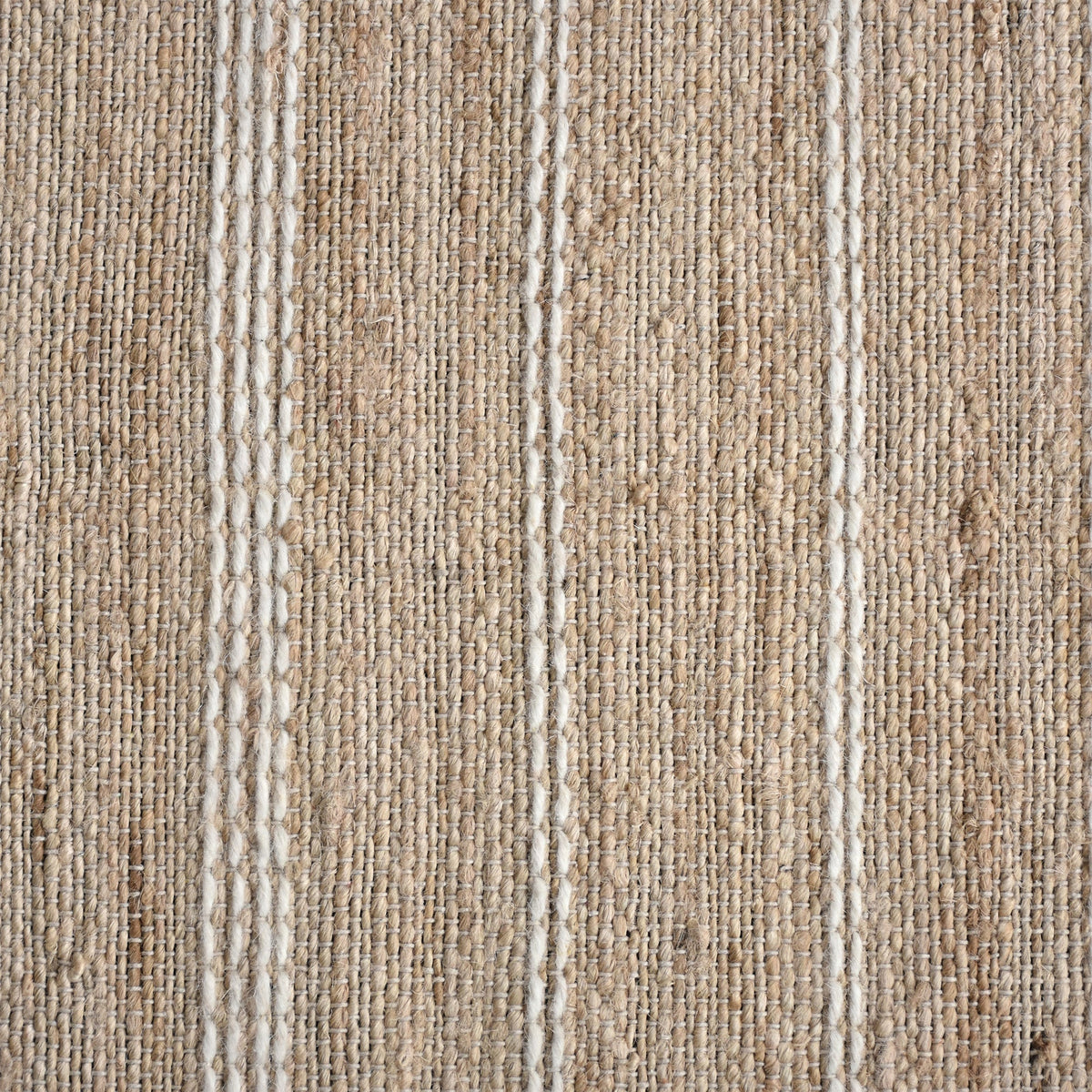 Taar handwoven wool and jute rug with fine vertical ribs in bleached natural and ivory, in a bedroom