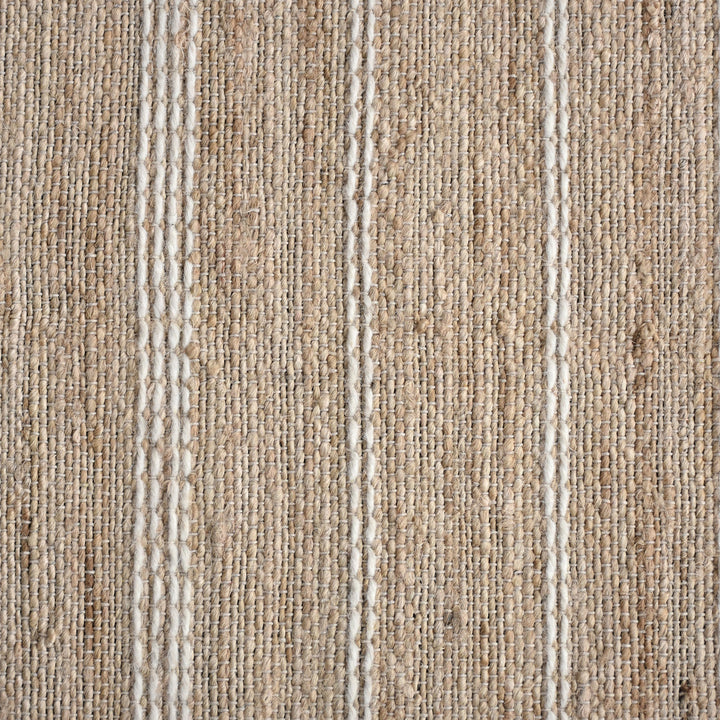 Taar handwoven wool and jute rug with fine vertical ribs in bleached natural and ivory, in a bedroom