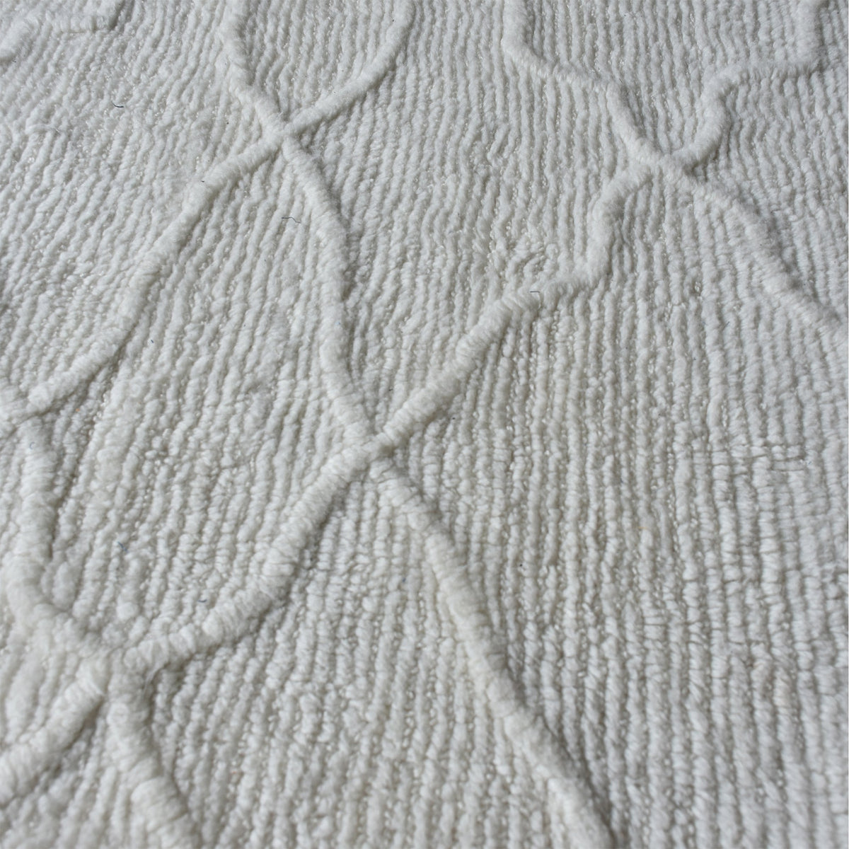 Kangan tufted wool rug with a tonal carved Moroccan lattice in bone ivory, in a bedroom