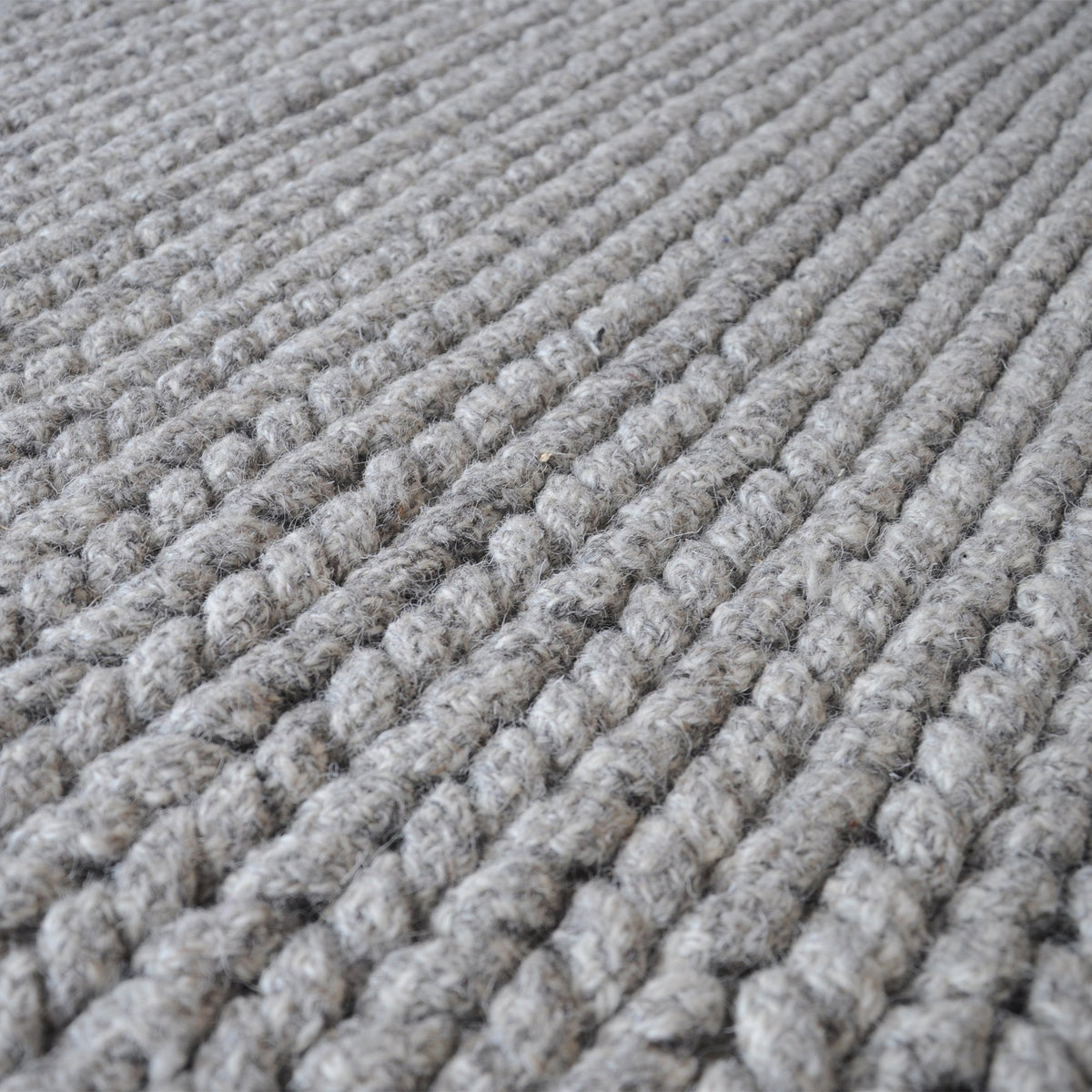 Dor handwoven chunky wool rug in charcoal, woven in thick cords, in a living room