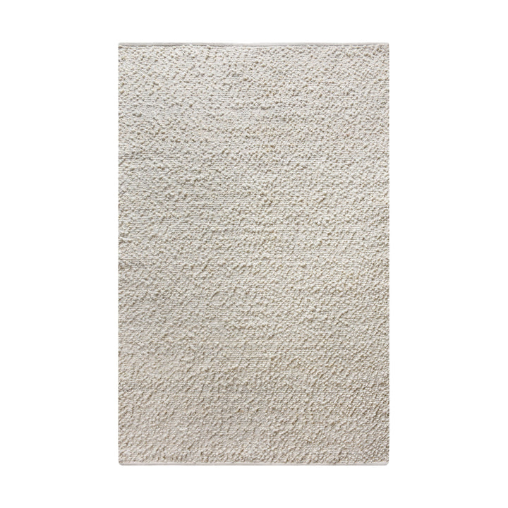 Lambswool handwoven ivory wool and jute rug with a bouclé pebble pile, in a living room