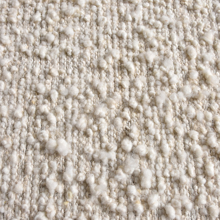 Lambswool handwoven ivory wool and jute rug with a bouclé pebble pile, in a living room