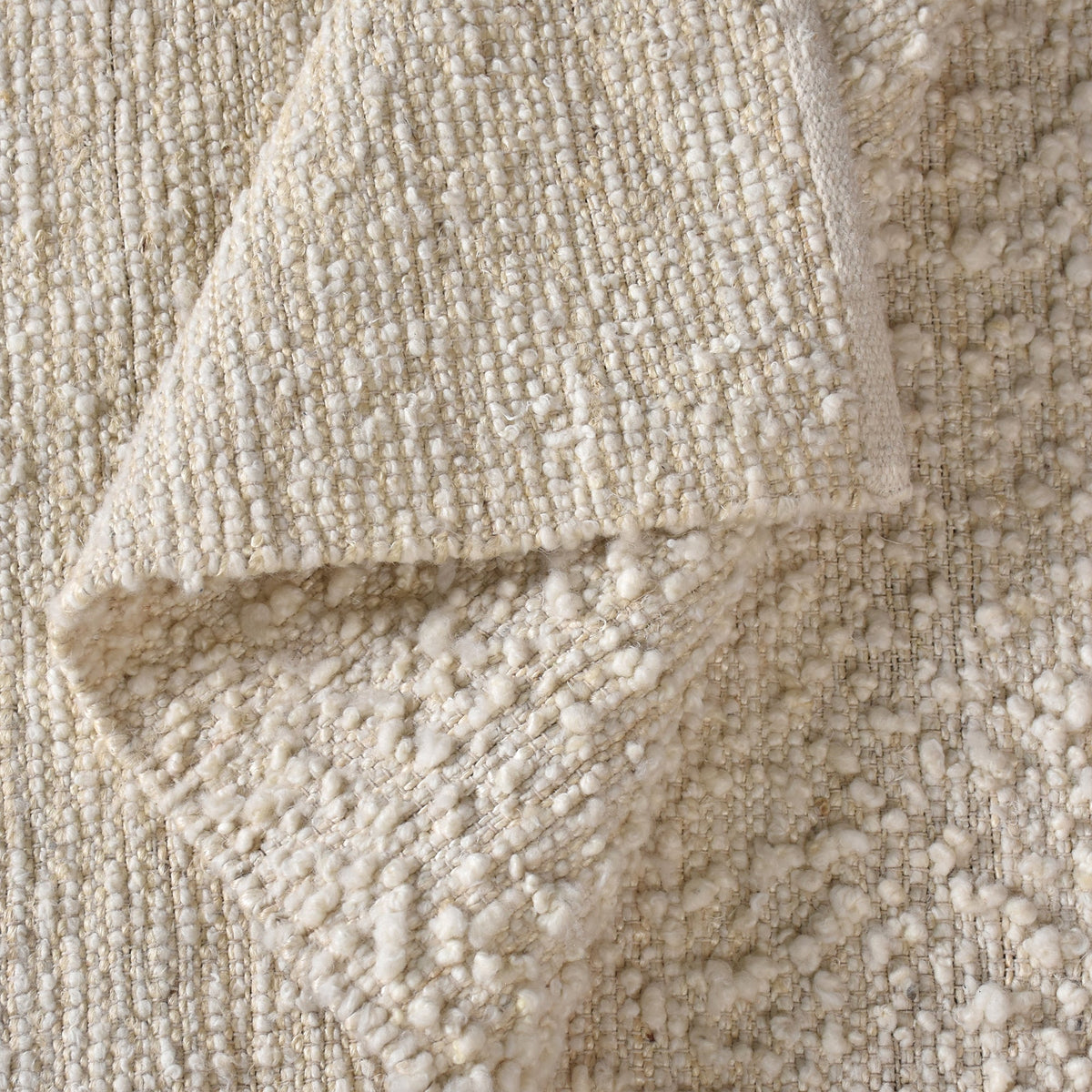 Lambswool handwoven ivory wool and jute rug with a bouclé pebble pile, in a living room