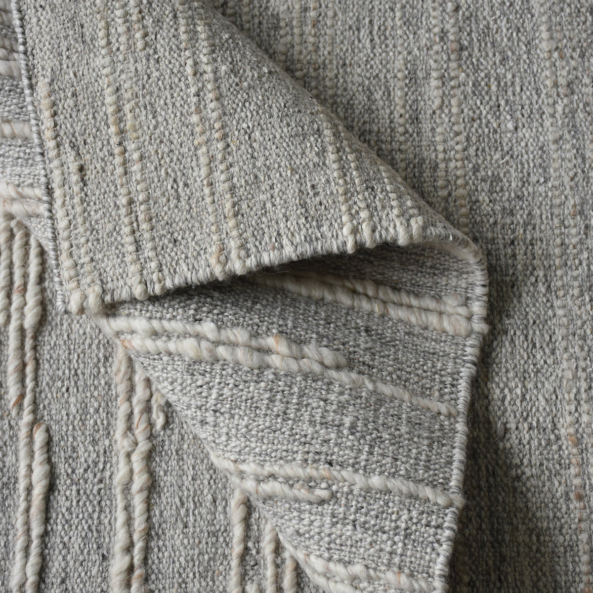 Surma hand-knotted wool rug in slate grey with raised ivory vertical stripes, in a living room