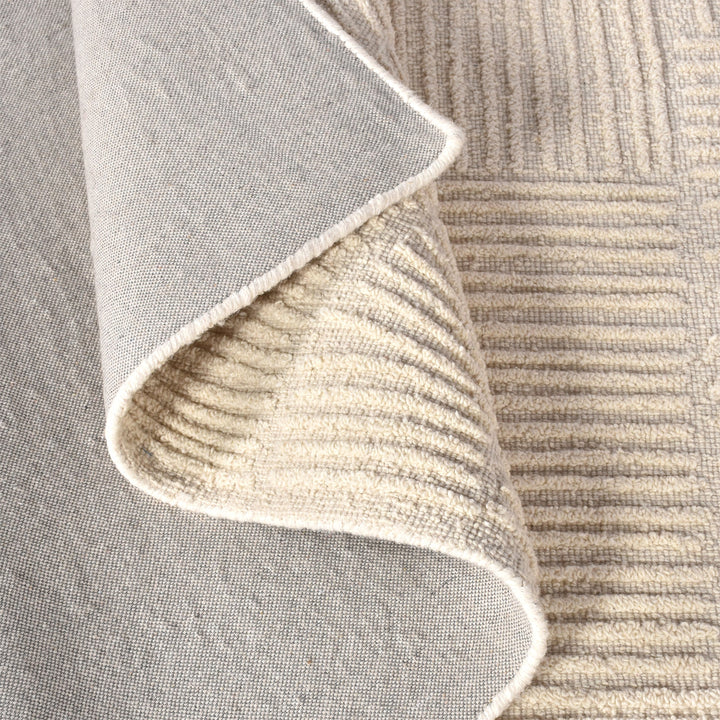 Kona handwoven cream wool rug with fine carved linear geometry, in a bedroom