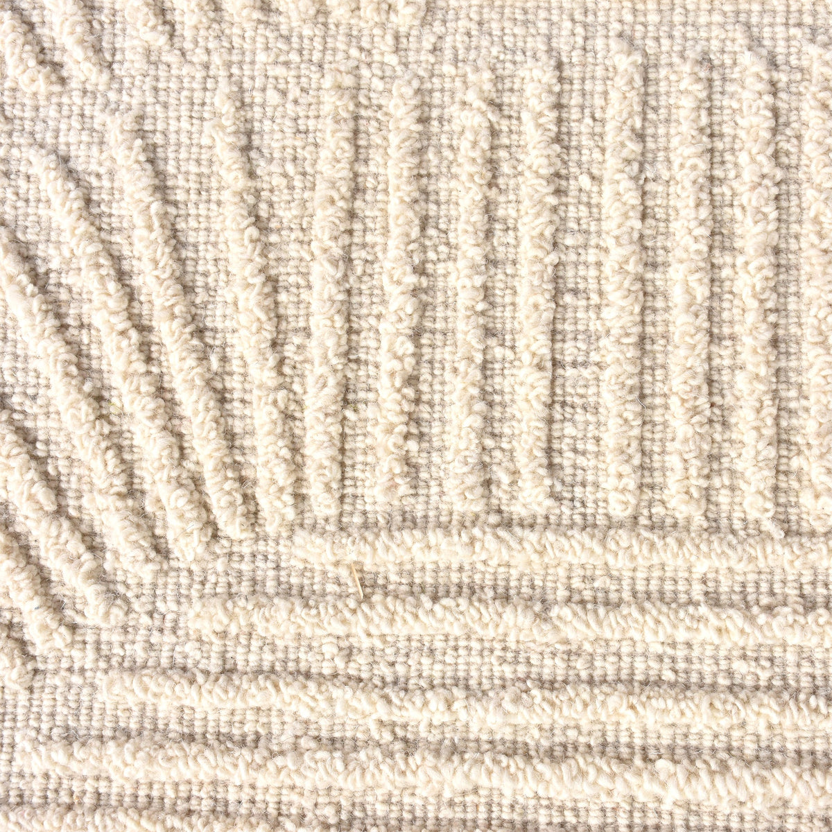 Kona handwoven cream wool rug with fine carved linear geometry, in a bedroom