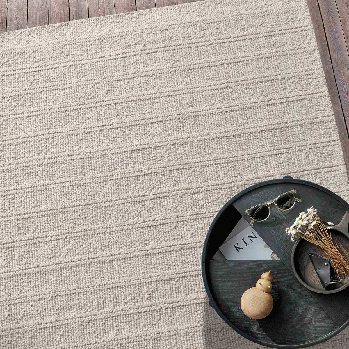 Oon handwoven ribbed wool rug in undyed oatmeal with horizontal ribs, under a coffee table