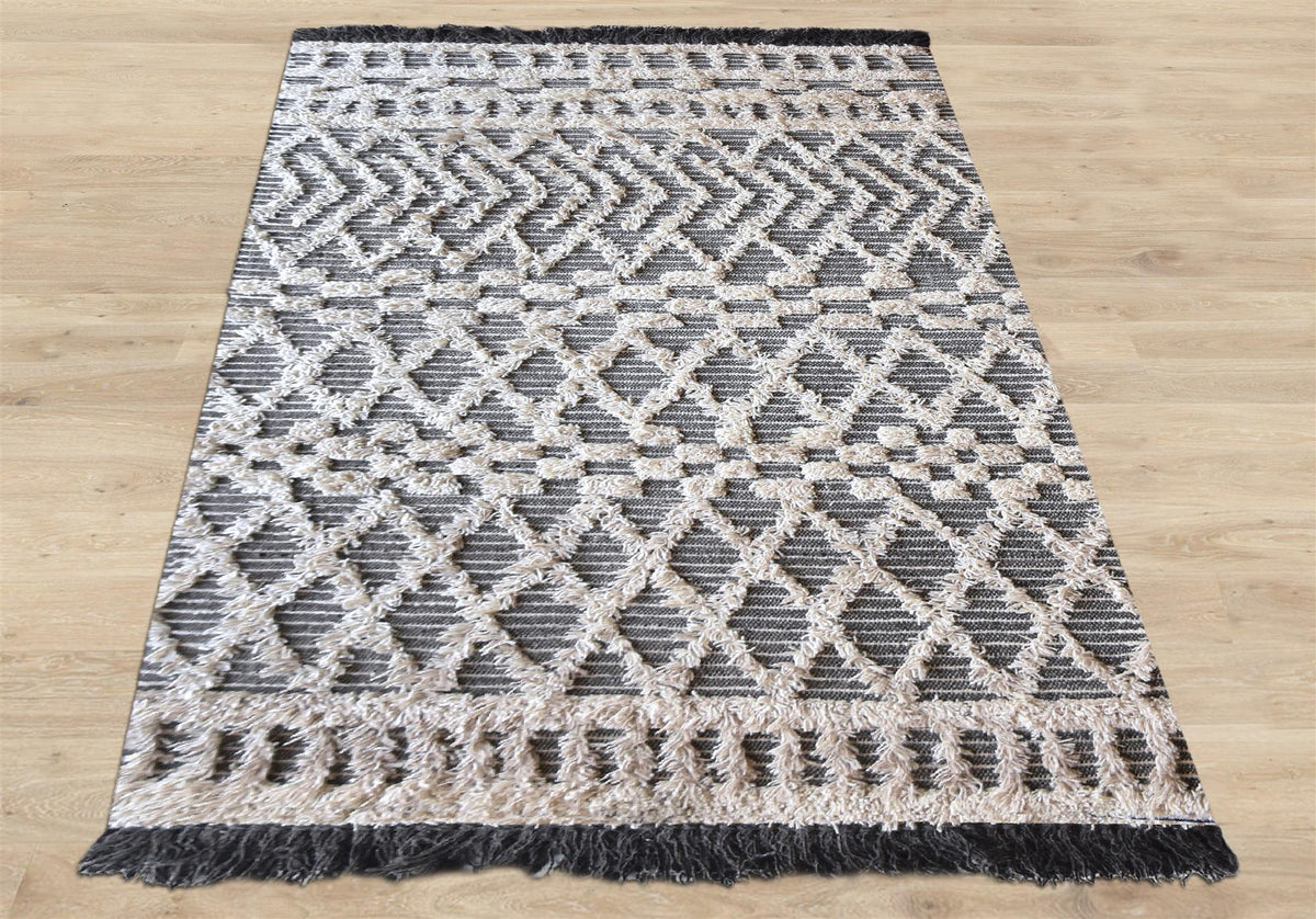 Tassel tufted wool rug with charcoal and ivory chevrons and shaggy bands, in a bedroom