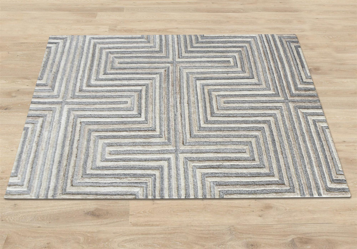 Raasta hand-tufted sand beige wool rug with carved concentric maze lines, in a living room