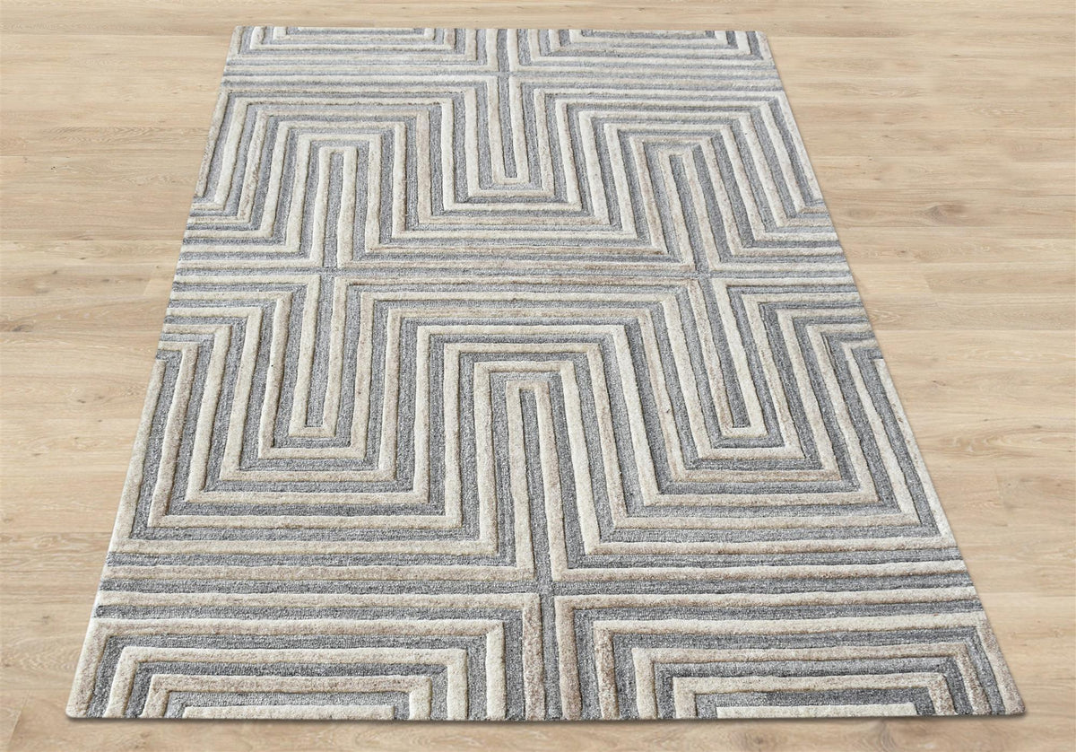 Raasta hand-tufted sand beige wool rug with carved concentric maze lines, in a living room