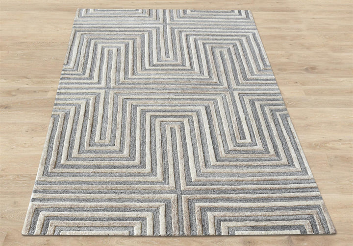 Raasta hand-tufted sand beige wool rug with carved concentric maze lines, in a living room