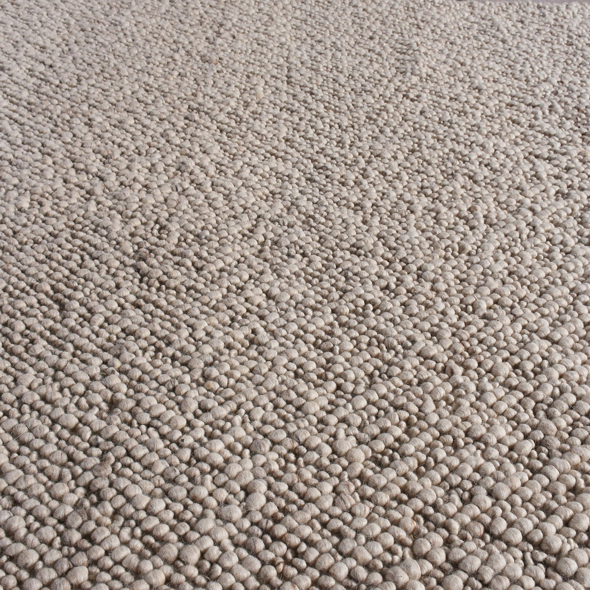 Mitti handwoven wool rug with a nubby looped weave in warm beige and brown, in a living room