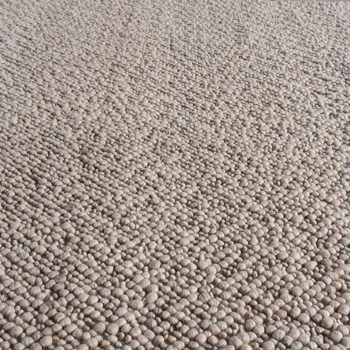 Mitti handwoven wool rug with a nubby looped weave in warm beige and brown, in a living room