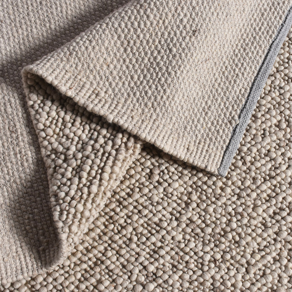 Mitti handwoven wool rug with a nubby looped weave in warm beige and brown, in a living room